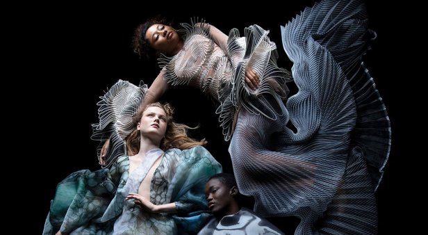 Three models float in black space wearing sculptural gowns.